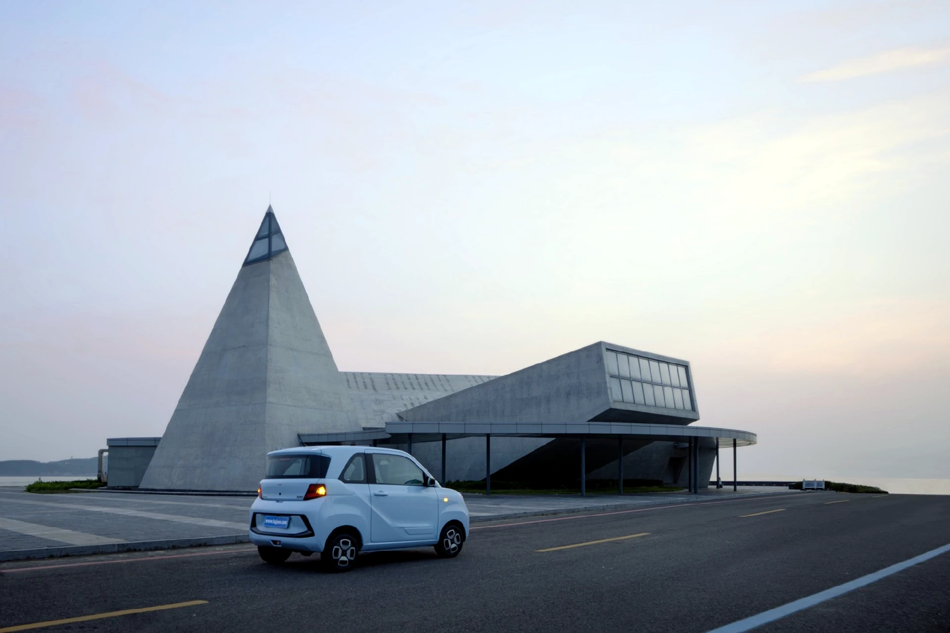 LOJO electric vehicle on a coastal road at dusk